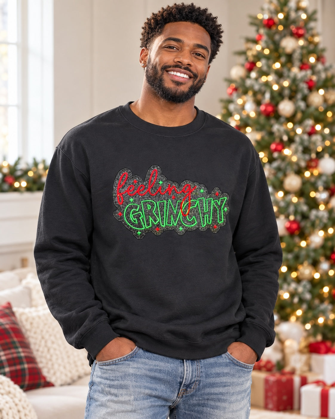 Untapped Innovations black crewneck sweatshirt with Feeling Grinchy glitter graphic worn by a smiling man