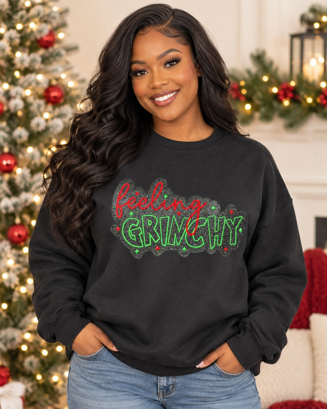Untapped Innovations black crewneck sweatshirt with Feeling Grinchy glitter graphic worn by a woman near a tree.