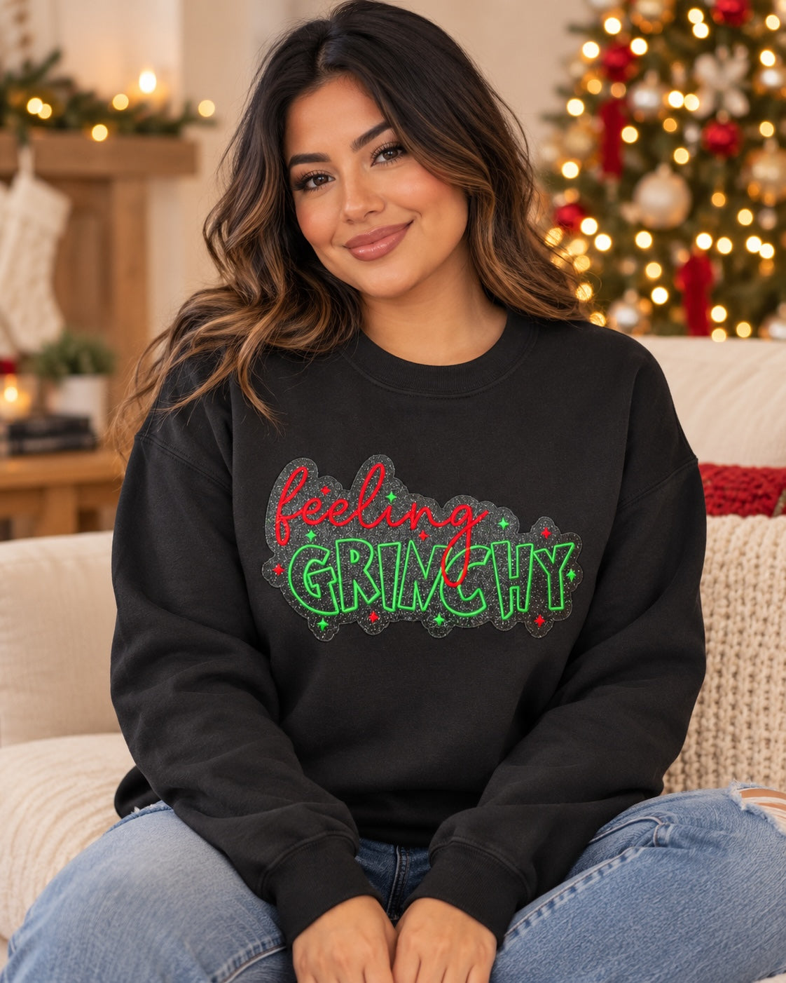 Woman wearing an Untapped Innovations black crewneck sweatshirt with a festive Feeling Grinchy glitter graphic