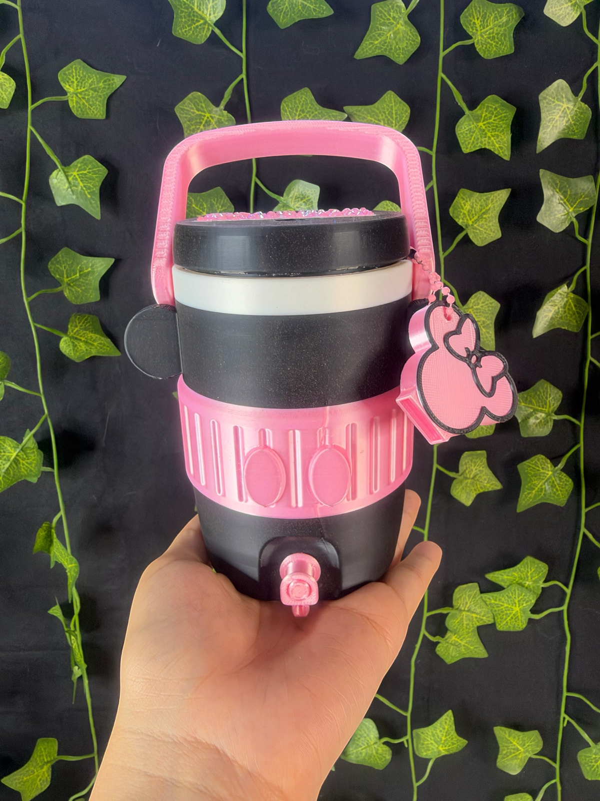 Untapped Innovations character-inspired portable beverage dispenser in black and pink with a spigot and handle.