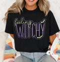 Untapped Innovations black crewneck t-shirt with Feeling Witchy glitter graphic, purple and neon green bat accents.