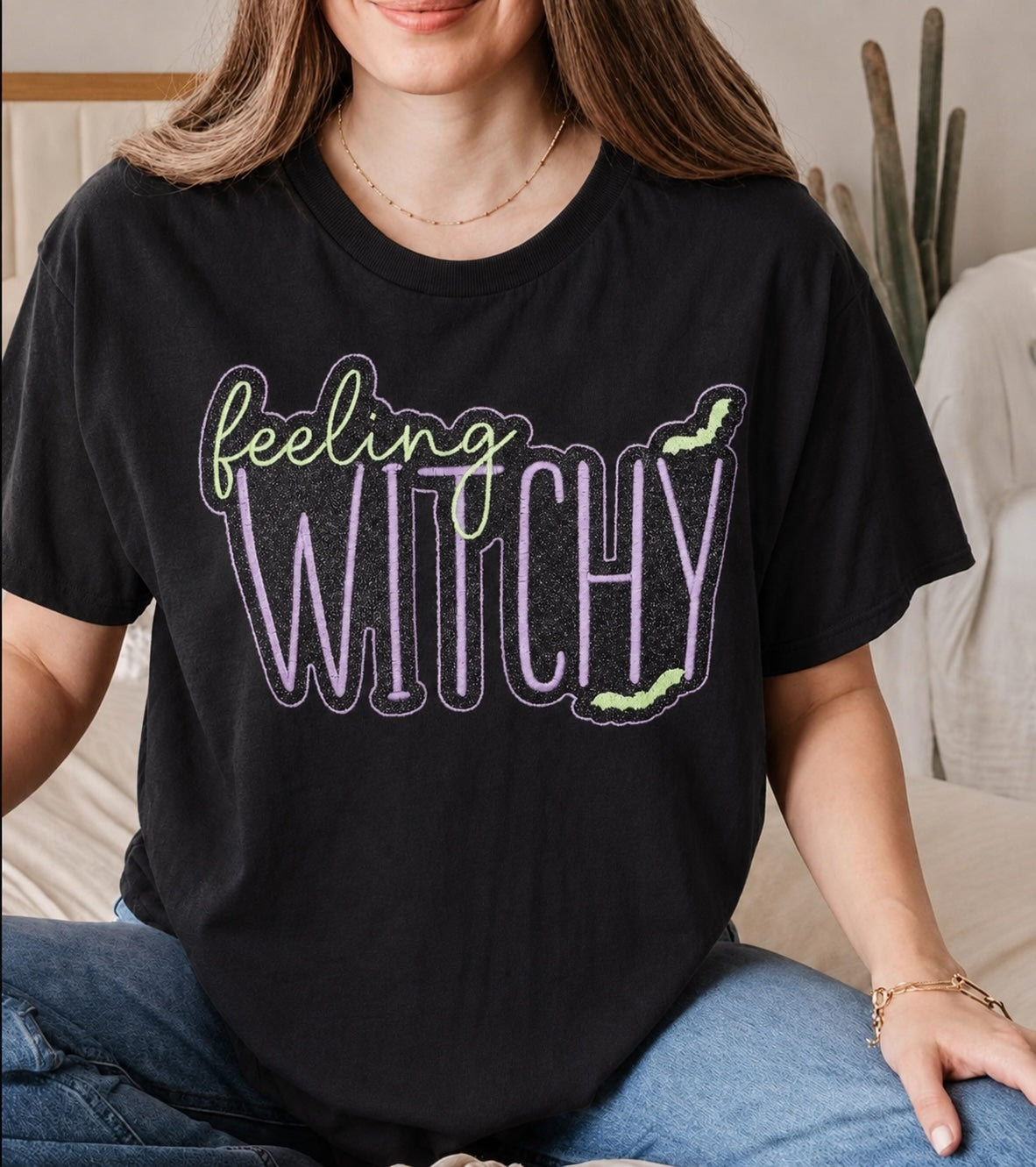 Untapped Innovations black crewneck t-shirt with Feeling Witchy glitter graphic, purple and neon green bat accents.