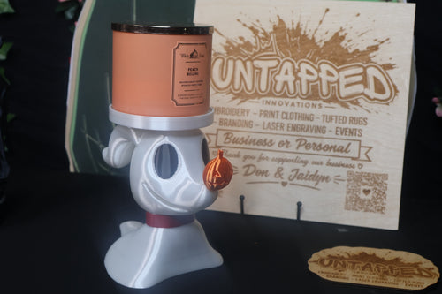 Untapped Innovations pearlescent white ghost dog candle holder with a glossy orange pumpkin nose holding a peach candle