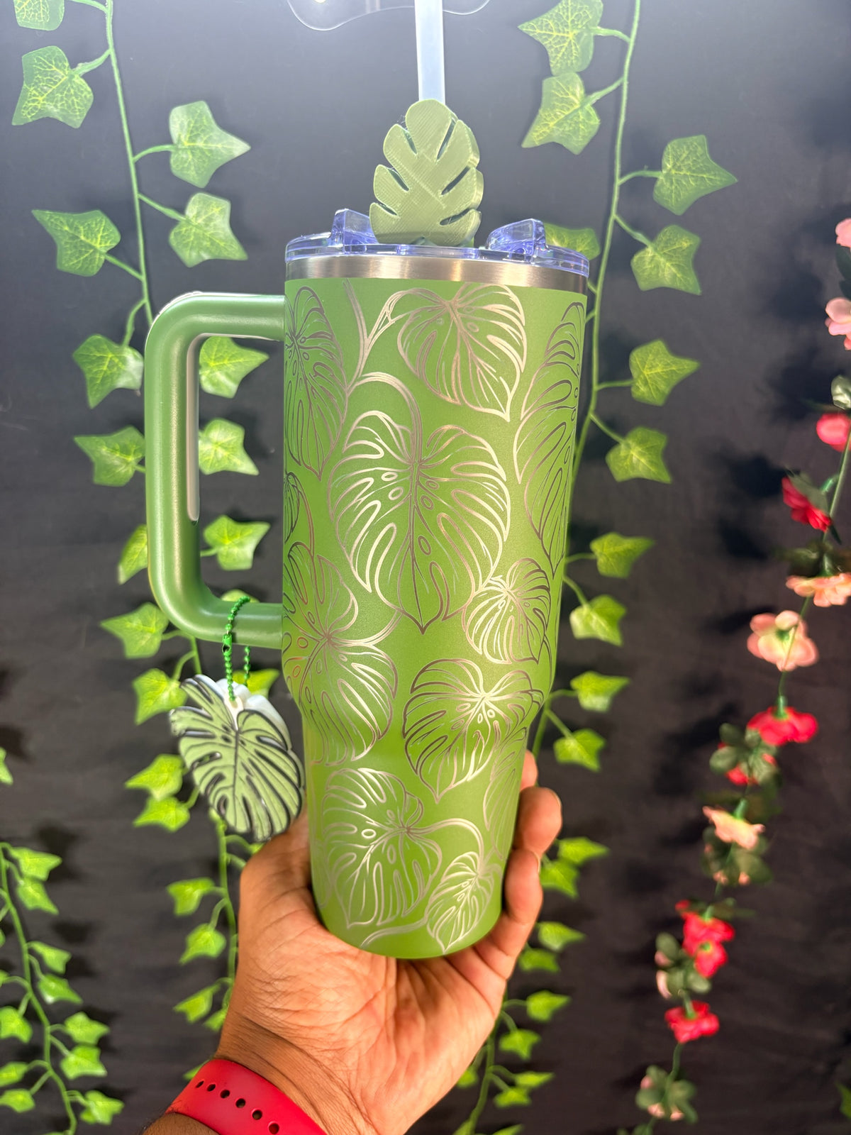 Untapped Innovations green insulated stainless steel tumbler with etched monstera leaf pattern, handle, and leaf charm.