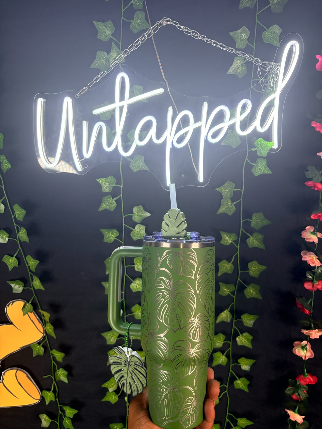 Untapped Innovations green stainless steel tumbler with etched monstera leaf pattern, handle, and leaf straw topper.