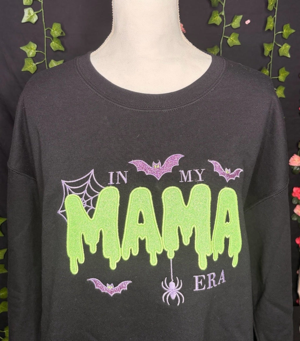 Untapped Innovations black crewneck sweatshirt with green slime MAMA text, purple glitter bats, and spider web design.