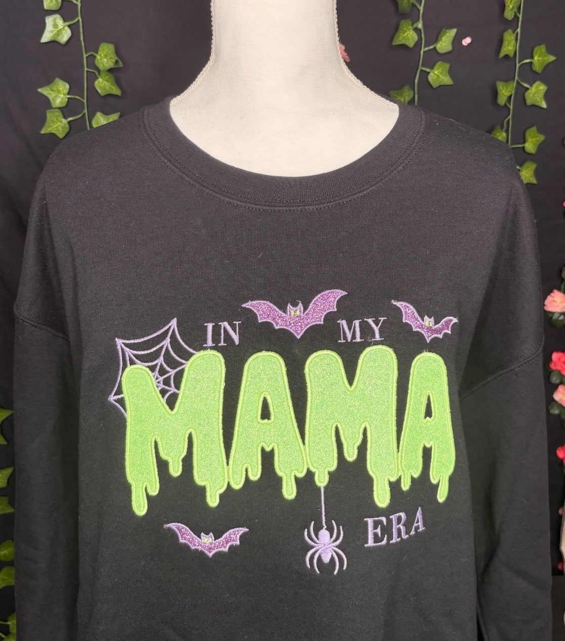Untapped Innovations black crewneck sweatshirt with green slime MAMA text, purple glitter bats, and spider web design.
