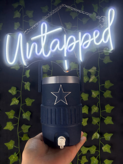 Untapped Innovations navy blue insulated beverage cooler with a star emblem and carry handle held in hand