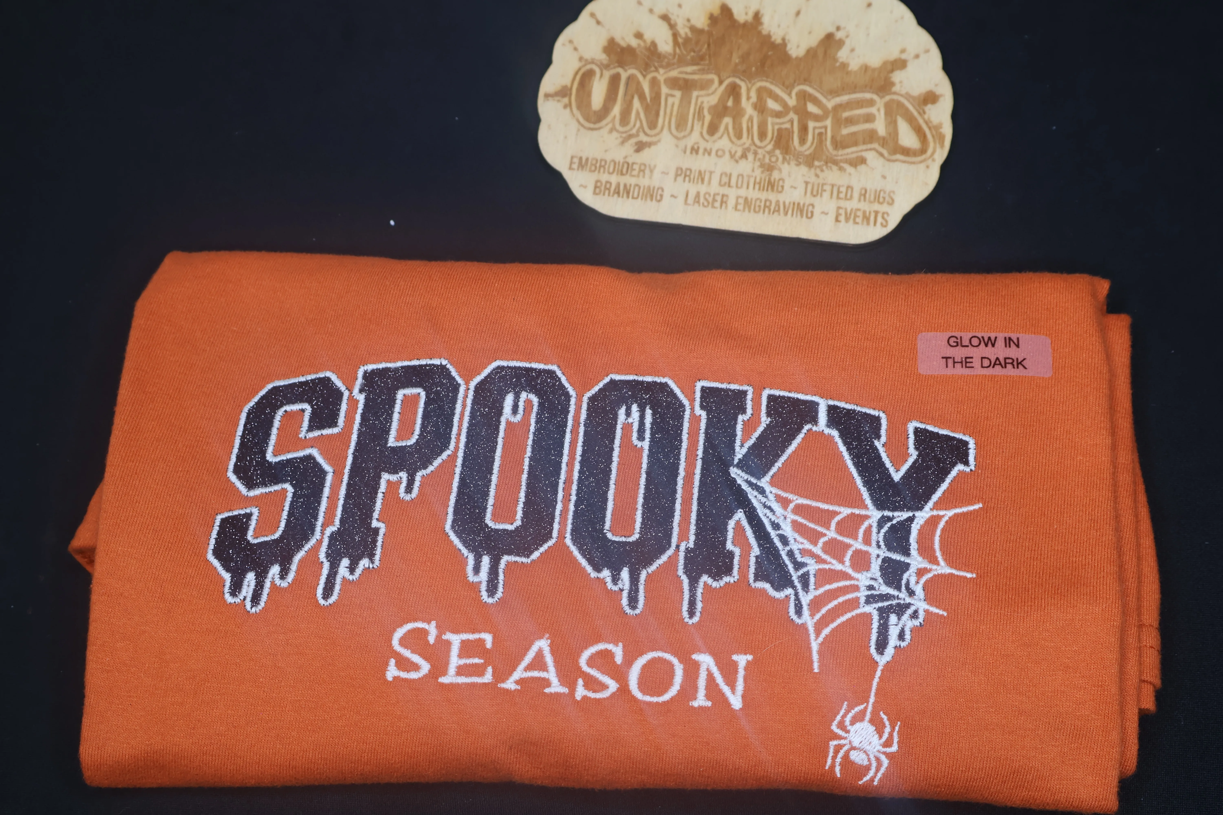 Untapped Innovations orange cotton t-shirt with glow-in-the-dark Spooky Season embroidery and spiderweb design
