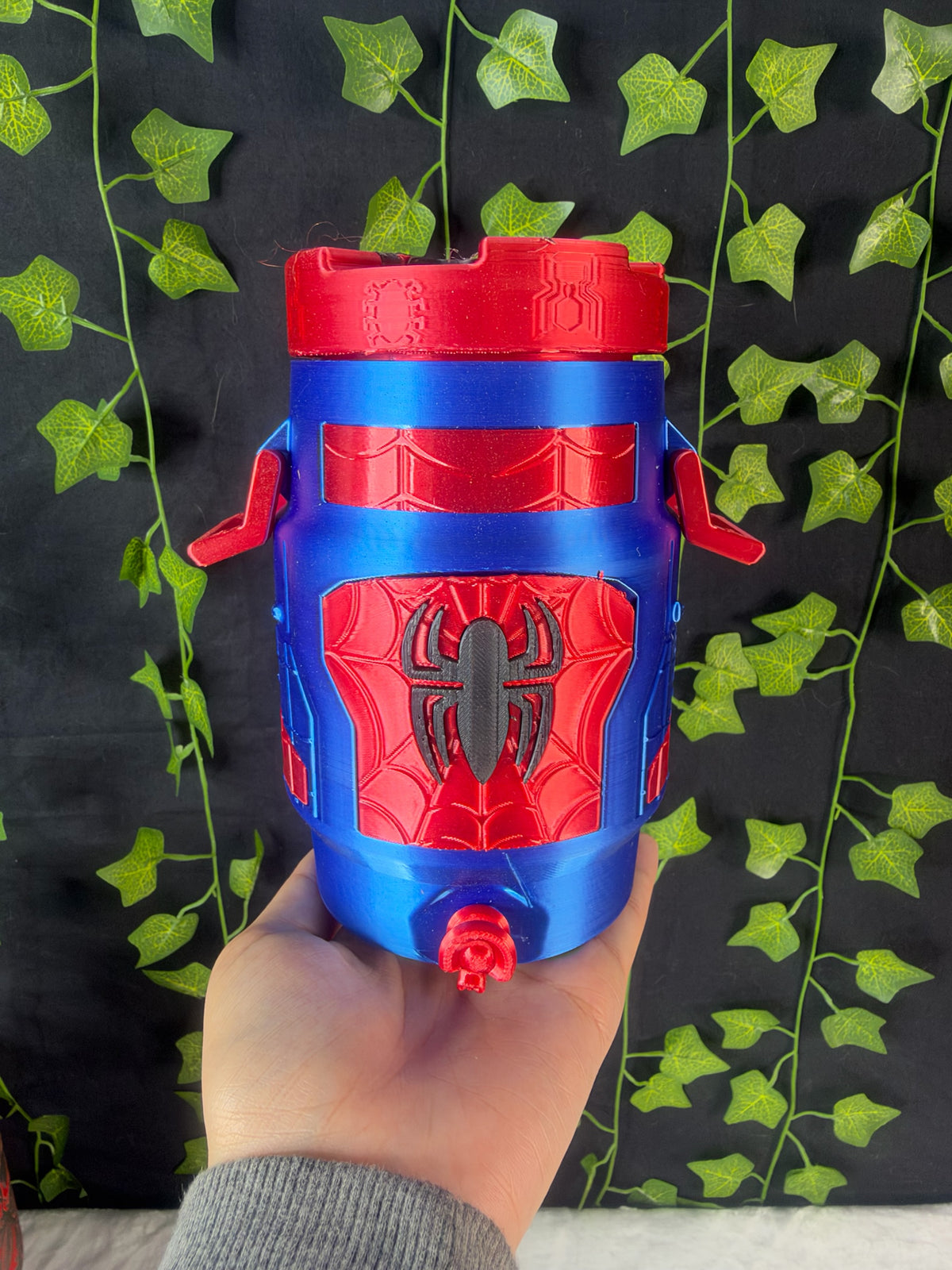 Untapped Innovations superhero themed insulated beverage dispenser in red and blue with a spider emblem and web pattern.